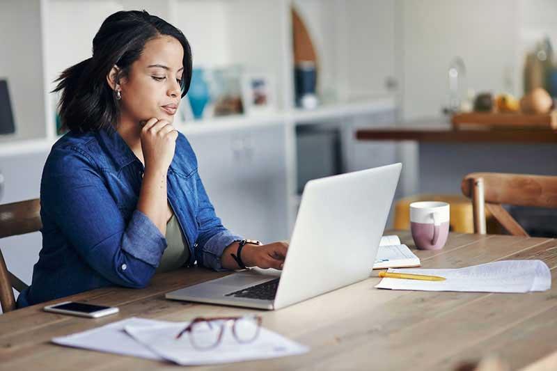 woman at table looking at laptop